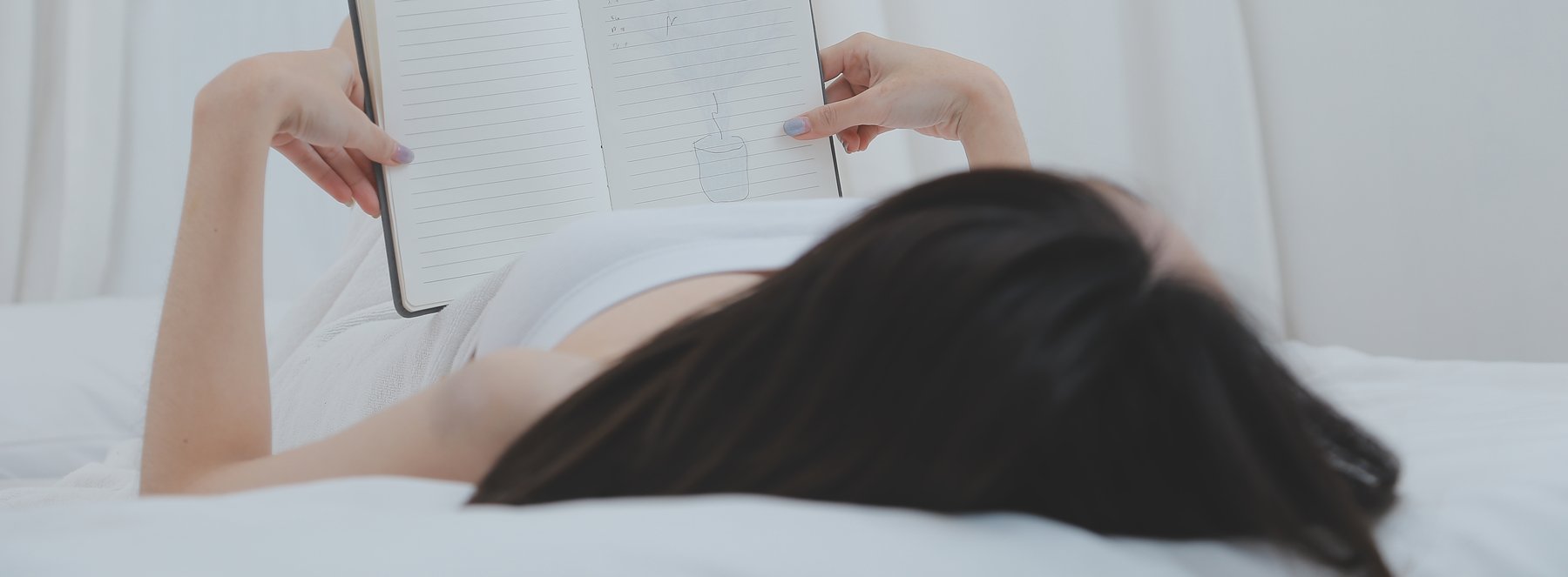 침대에 누워 노트에 기록하는 여성 참고 이미지